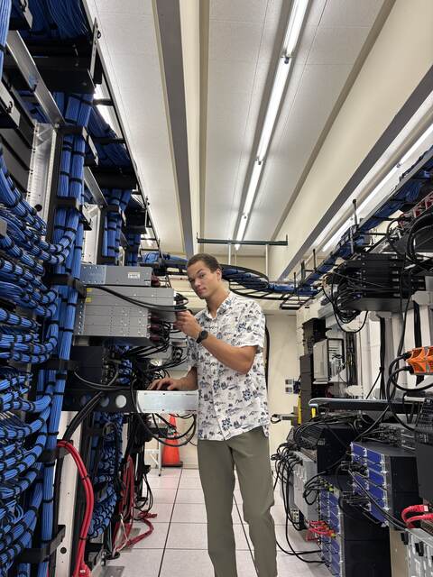 Carlos Eckert installing a server in a data center rack row surrounded by blue network cabling